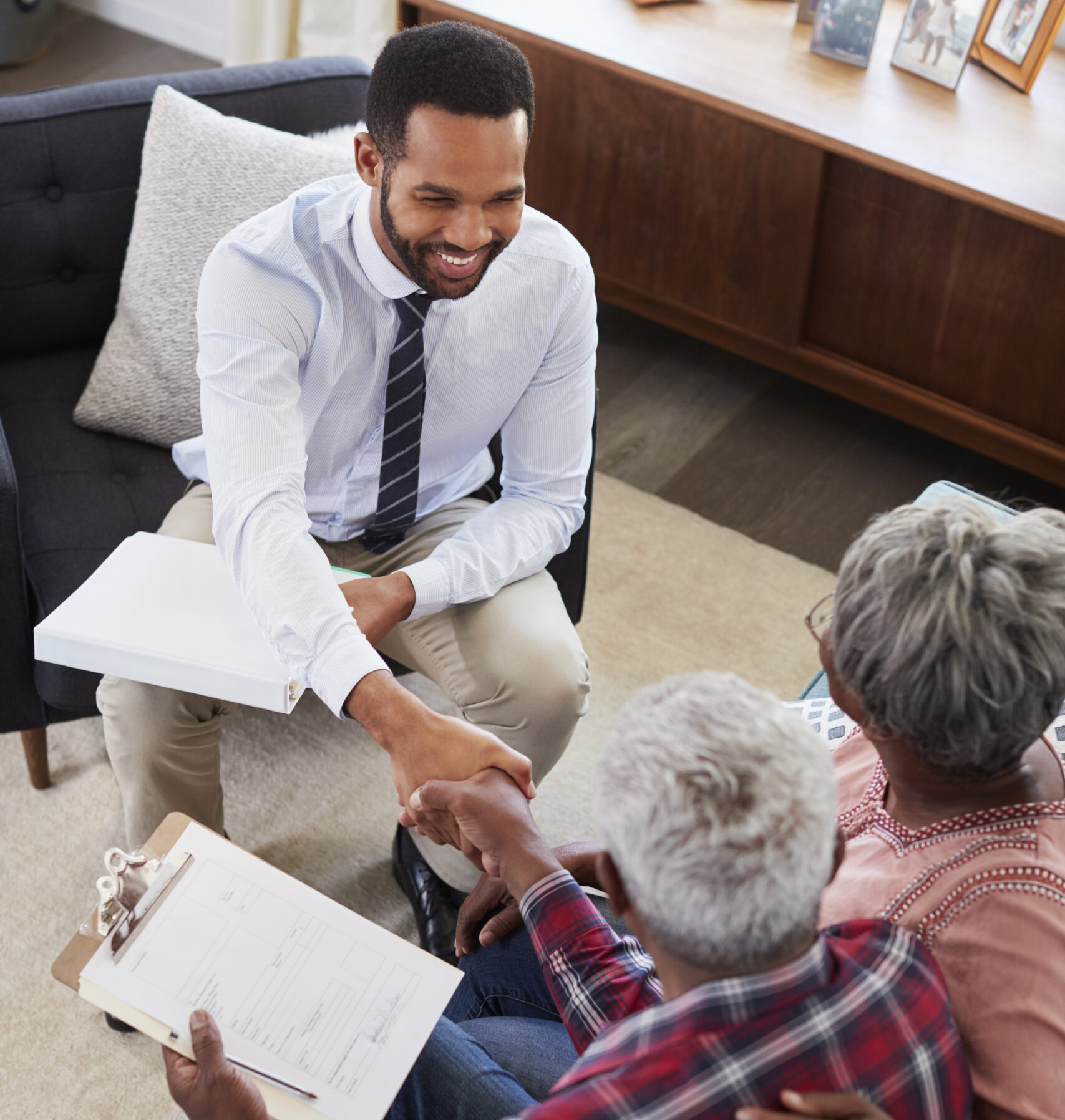 Senior Couple Shaking Hands With Male Financial Advisor At Home