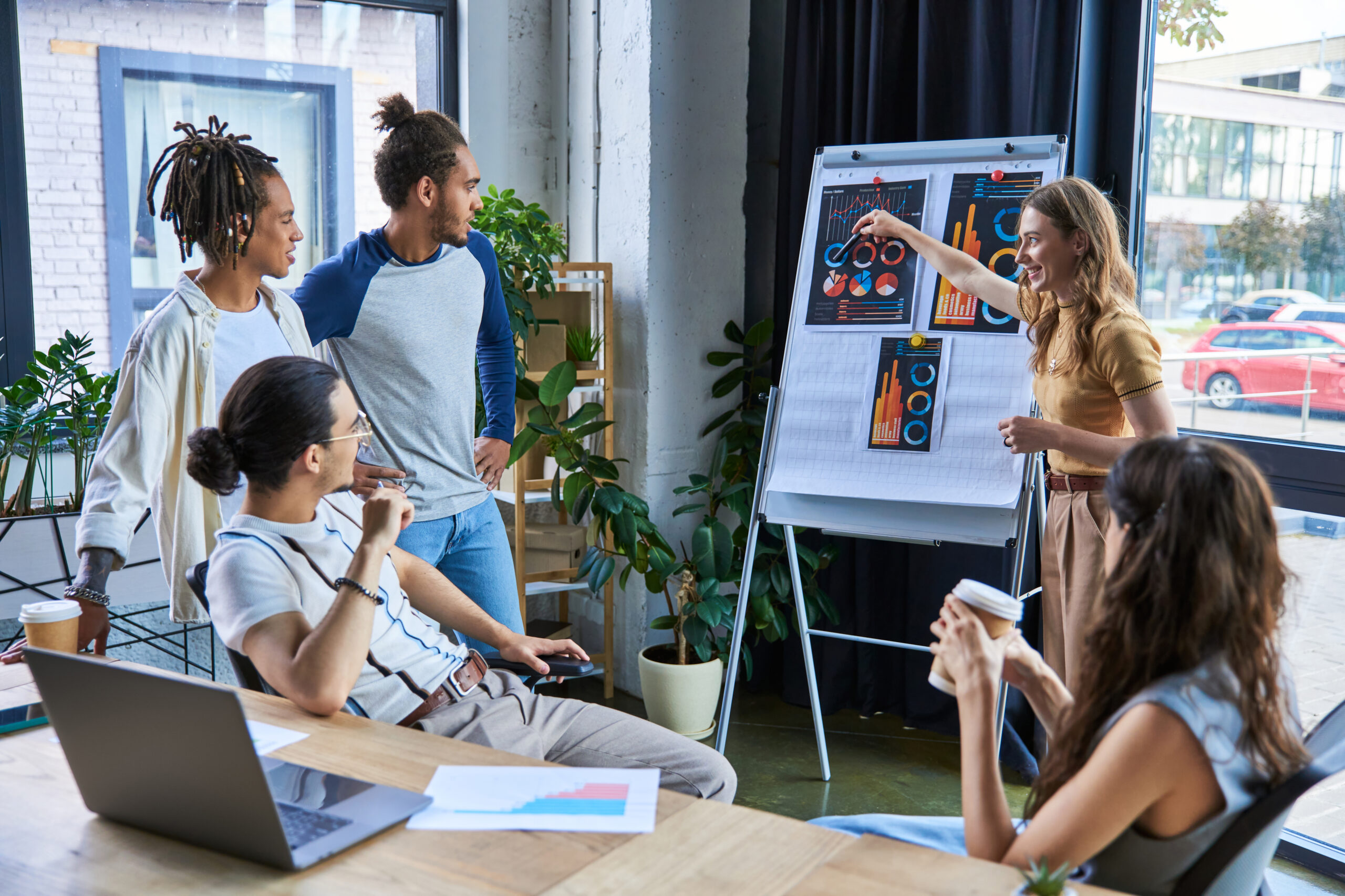 businesswoman pointing at flip chart  and discussing startup project with multiethnic colleagues